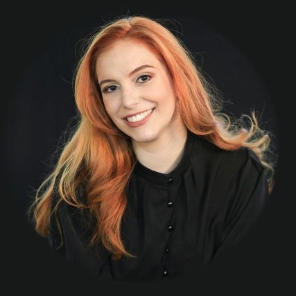Júlia Soares Vieira, de cabelo ruivo e blusa preta, sorrindo